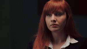 Closeup of redheaded woman in business attire in a dark room