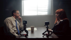 Man interrogating a woman in an office environment